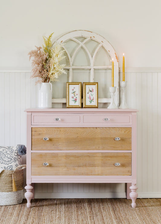 Dresser with wooden drawers and Homestead House Milk Paint in Bouquet pink base, decorated with candles and a mirror.