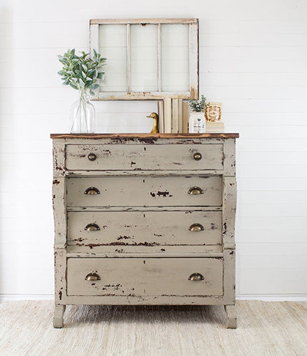 Algonquin milk painted Vintage-style dresser with heavily chipped taupe beige paint and a wooden top against a white shiplap wall