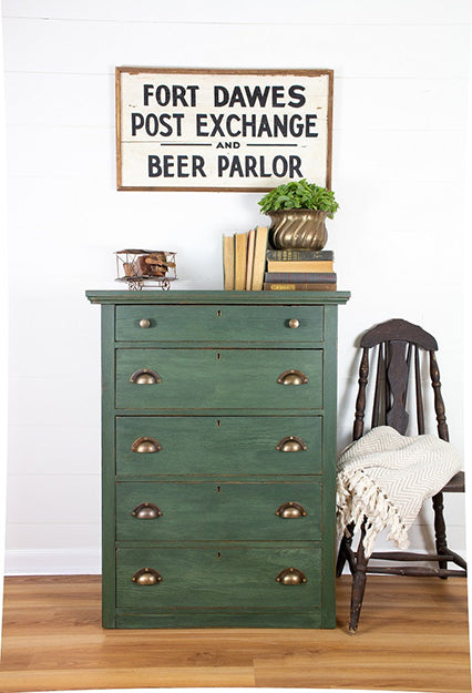 Natural textures created with Bayberry Homestead House Milk Paint on dresser with brass knobs in a room with a sign above it.