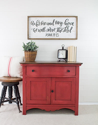 Fort York Red cabinet painted in milk paint with a sueded texture and a wooden top, decorative items, and a framed quote on a white wall.