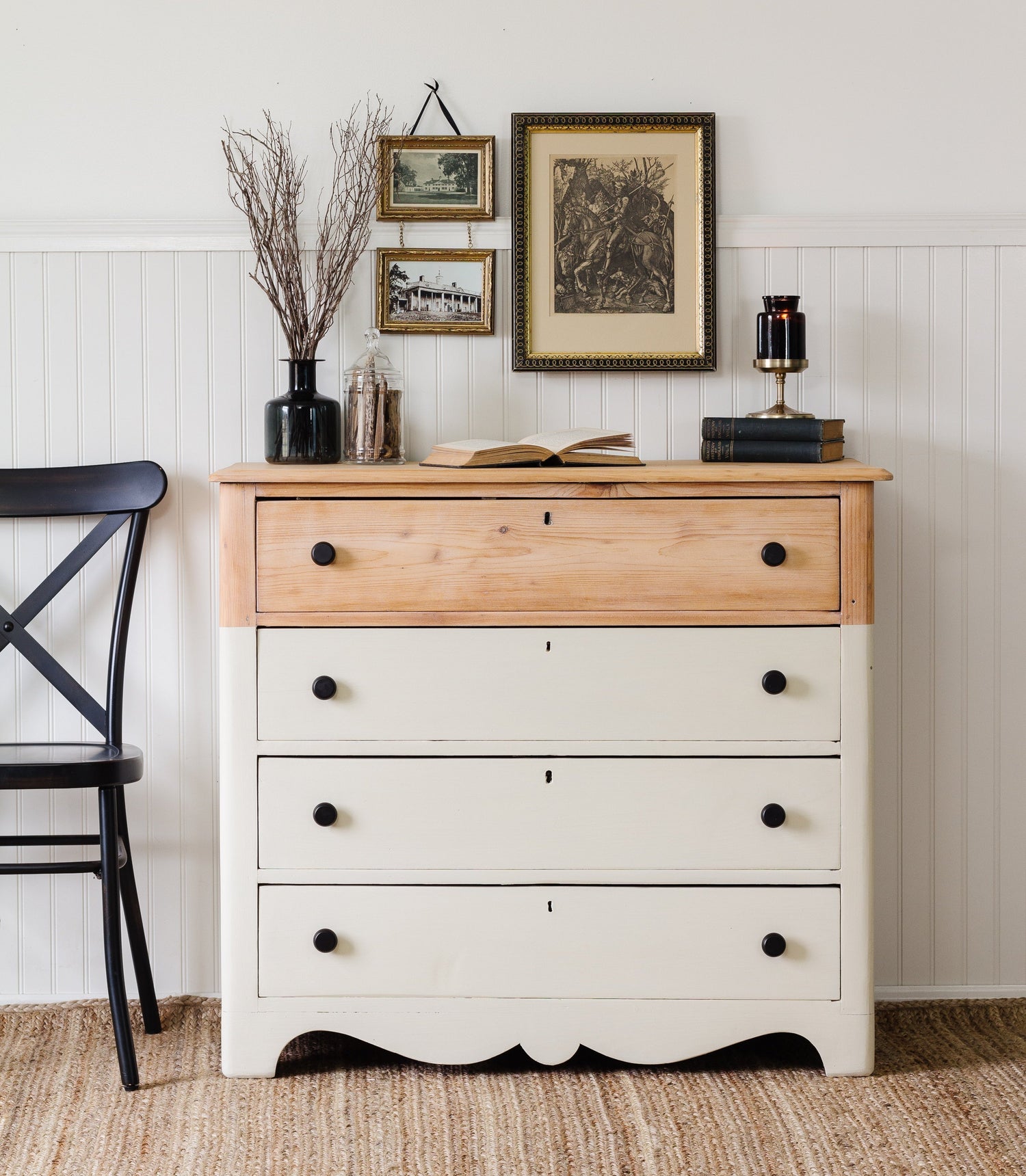 Wooden dresser with Stone Fence off white bottom half and natural wood top half, decorated with books and vases