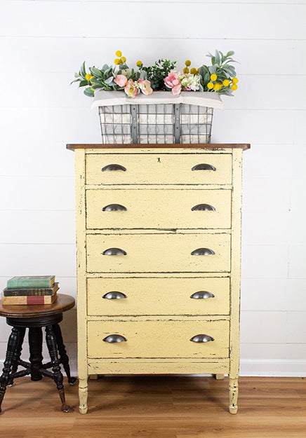 Vintage Yellow Ochre dresser with floral arrangement on a white wall background