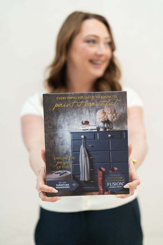 Jennylyn founder of Fusion Mineral Paint holding her book